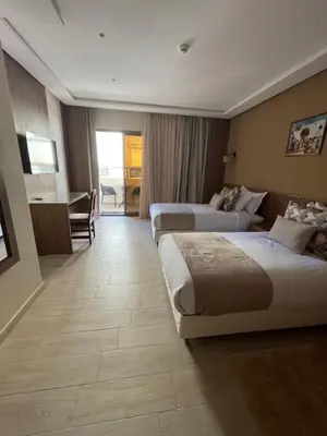 a hotel room with two beds and a desk at Hotel De Nice in Meknès