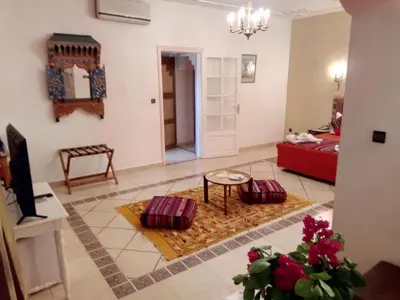 a living room with a red couch and a table at Hôtel Le Tinsouline in Zagora