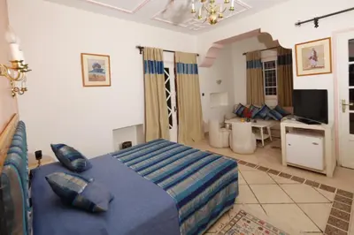 a bedroom with a blue bed and a living room at Hôtel Le Tinsouline in Zagora