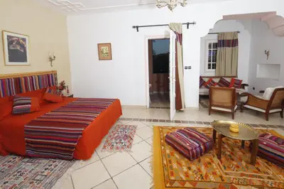 a bedroom with a bed and a living room at Hôtel Le Tinsouline in Zagora