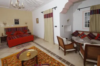 a living room with a red couch and a table at Hôtel Le Tinsouline in Zagora