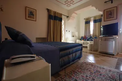 a bedroom with a bed and a living room at Hôtel Le Tinsouline in Zagora