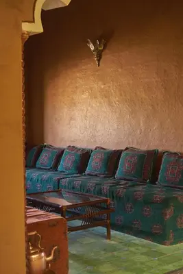 a living room with a couch with blue pillows at Hotel Kasbah Azalay in Mhamid