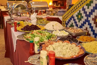 a table with many plates of food on it at Hotel Kasbah Azalay in Mhamid