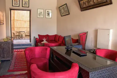 a living room with red chairs and a desk at Hotel Azoul in Ouarzazate