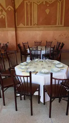 a group of tables and chairs with plates on them at Hotel Mandar Saghrou Tazakhte in Kalaat MGouna