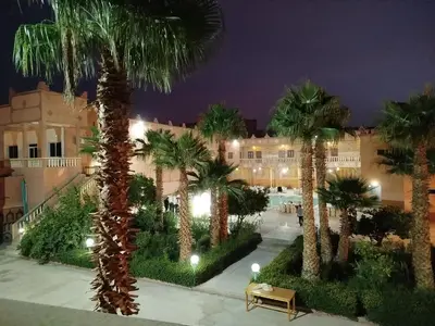 a courtyard with palm trees in front of a building at Hotel Mandar Saghrou Tazakhte in Kalaat MGouna