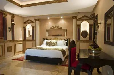 a bedroom with a bed and a table and a desk at Le Temple Des Arts in Ouarzazate