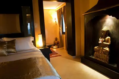 a bedroom with a bed and a statue next to a fireplace at Le Temple Des Arts in Ouarzazate