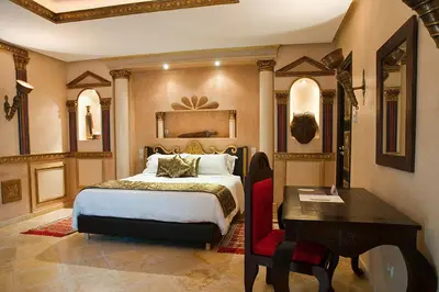 a bedroom with a bed and a table and a desk at Le Temple Des Arts in Ouarzazate