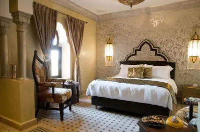 a bedroom with a large bed and a chair at Le Temple Des Arts in Ouarzazate