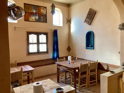 a dining room with two tables and a window at Les 4 Saisons Du Dades in Aït Idaïr