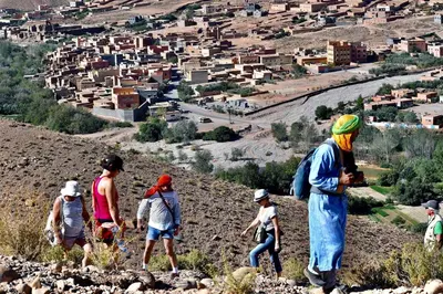 a group of people walking on a hill overlooking a city at Les 4 Saisons Du Dades in Aït Idaïr