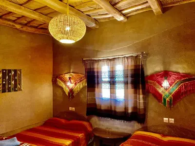 a room with two beds and a window and a chandelier at Les 4 Saisons Du Dades in Aït Idaïr