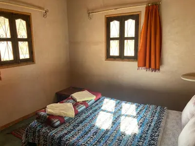 a bedroom with a bed and two windows at Les 4 Saisons Du Dades in Aït Idaïr