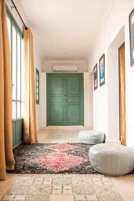 a room with two ottomans in front of a green door at Jnane Allia in Douar Soukkane