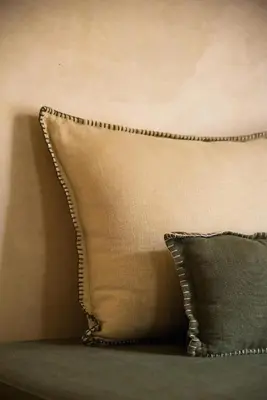 a beige couch with a pillow and a wall at Jnane Allia in Douar Soukkane