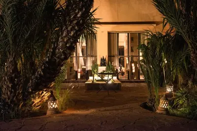 a courtyard with plants and a table with lights at Jnane Allia in Douar Soukkane