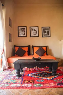 a bedroom with a bed with orange pillows and a rug at Jnane Allia in Douar Soukkane
