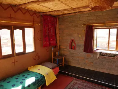 a room with a bed and two windows at Auberge Hostel Traditionnel in Tinerhir