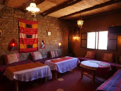 a restaurant with two tables and a flag on the wall at Auberge Hostel Traditionnel in Tinerhir