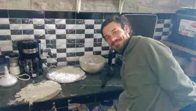 a man standing in front of a table with dough at Auberge Hostel Traditionnel in Tinerhir