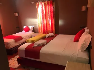 two beds in a room with red and white at Dar Talhaya in Kasr Bounou