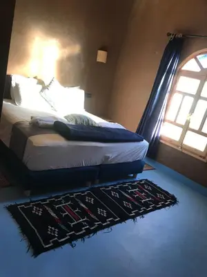 a bedroom with a bed with a rug and a window at Dar Talhaya in Kasr Bounou