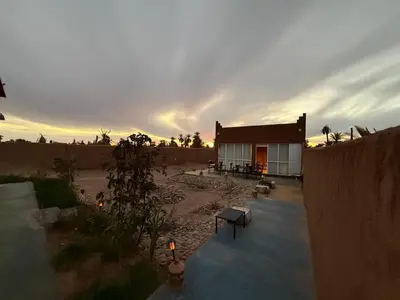 a building in the desert with a sunset in the background at Dar Talhaya in Kasr Bounou