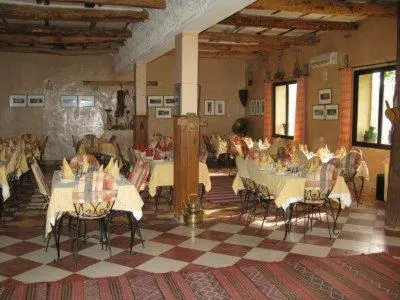 a large room with tables and chairs in a building at Riad Mimouna De Timnay in Aguelmous