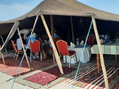 a tent with red chairs and a table in it at Riad Mimouna De Timnay in Aguelmous