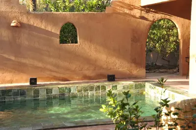 a swimming pool next to a building with two arches at Dar Sofar in Agdz