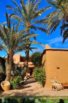 a resort with palm trees and a house with a pool at Dar Sofar in Agdz