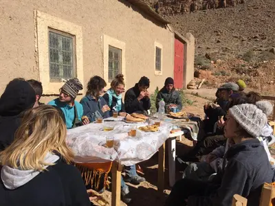 a group of people sitting around a table with food at Gîte d'étape traditionnel berbère in Ifri