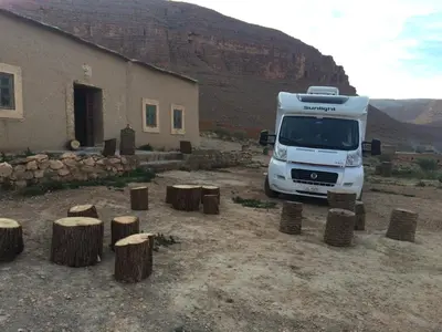 a white truck parked in front of a building with tree stumps at Gîte d'étape traditionnel berbère in Ifri