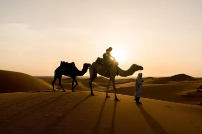 a man and two camel riders in the desert at Authentic riad & activities Erg in Mhamid