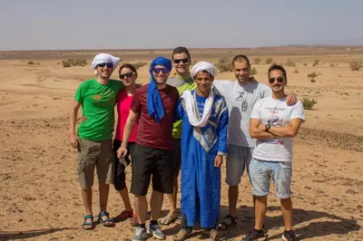 a group of people posing for a picture in the desert at Authentic riad & activities Erg in Mhamid
