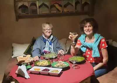 two women sitting at a table with plates of food at Maison d'Hôtes Irocha in Tisselday