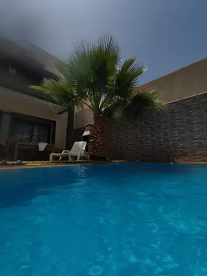 a large blue swimming pool with a palm tree at Villa Nour in Fès