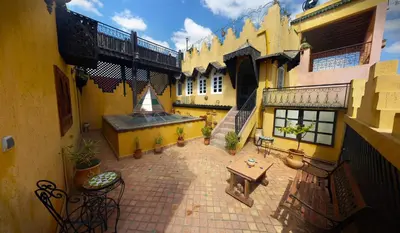 a courtyard of a building with a table and chairs at Riad Atika Mek in Meknès