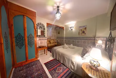 a bedroom with a bed and a room with a couch at Riad Atika Mek in Meknès
