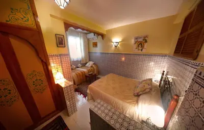 a bedroom with two beds and a living room at Riad Atika Mek in Meknès