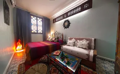 a bedroom with two beds and a table and a window at Riad Atika Mek in Meknès