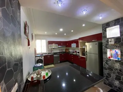 a small kitchen with red cabinets and a refrigerator at Sweet Jacob's Apartments in Fès