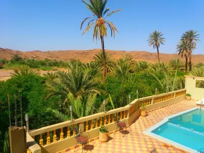 a resort with a swimming pool and palm trees at Kasbah Elmehdaoui in Skoura