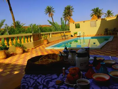a table with plates of food next to a swimming pool at Kasbah Elmehdaoui in Skoura