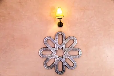 a metal cross and a light on a wall at Riad Azawad in Merzouga