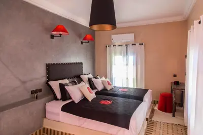a bedroom with a large bed with pink pillows at Riad Azawad in Merzouga