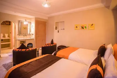 a hotel room with two beds and a bathroom at Riad Azawad in Merzouga