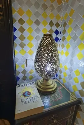 a vase sitting on a table next to a book at Palais didi in Meknès